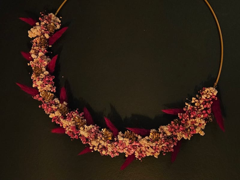 Demi-couronne rose framboise, crème et pommes de pin dorées sur cerceau doré